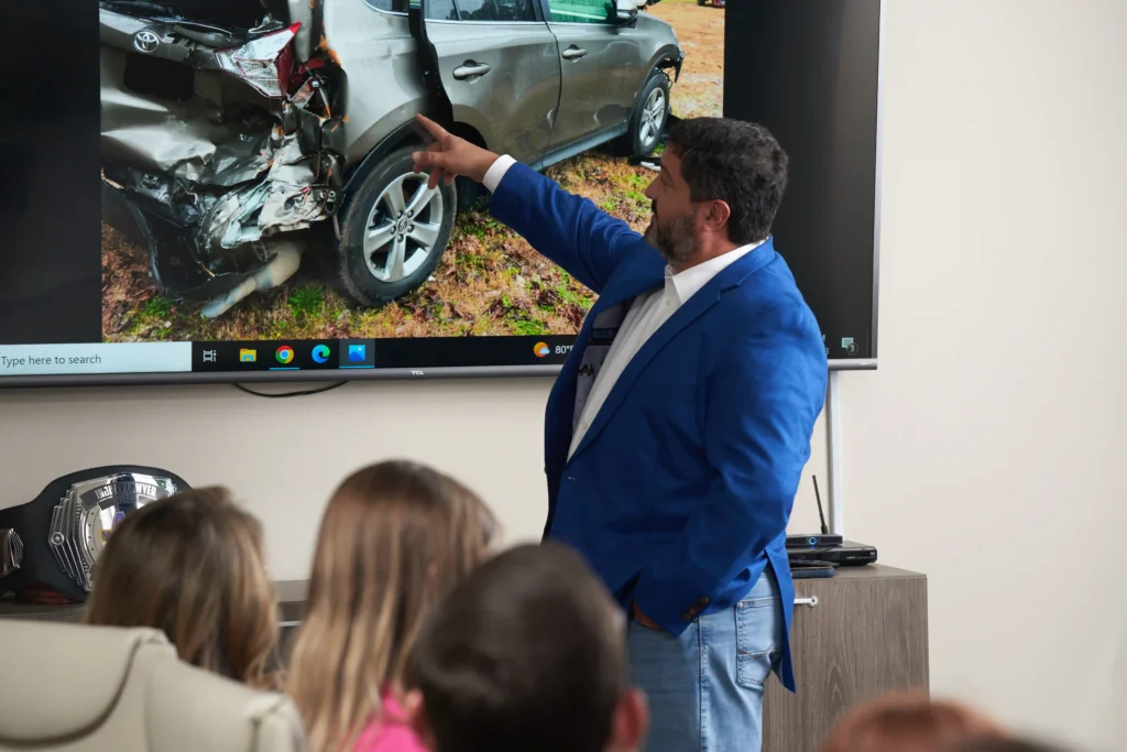 Steven Mezrano presenting car accident picture to Mezrano® Law Firm staff