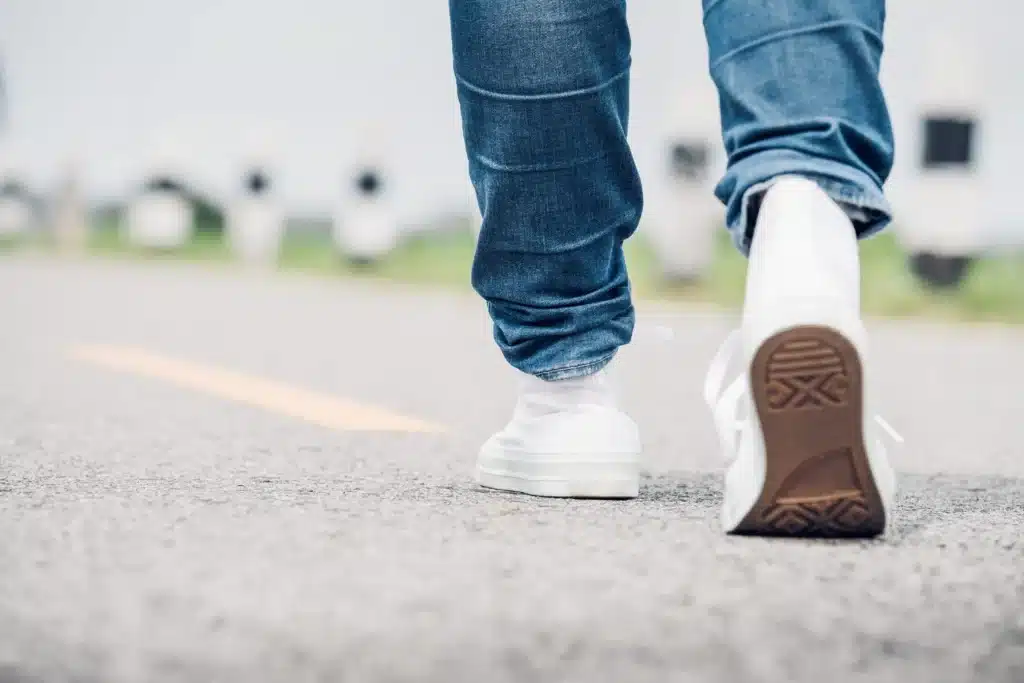Closeup of mans feet walking on side of road