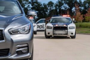 Two police vehicles stop a sedan during a routine traffic stop.