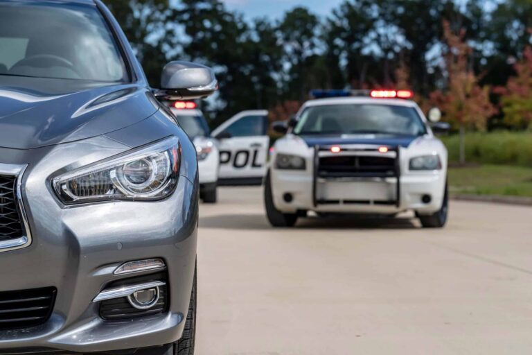 Two police vehicles stop a sedan during a routine traffic stop.
