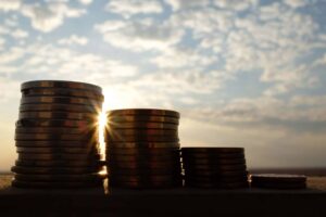 A decreasing stack of coins at sunset showing financial loss concept