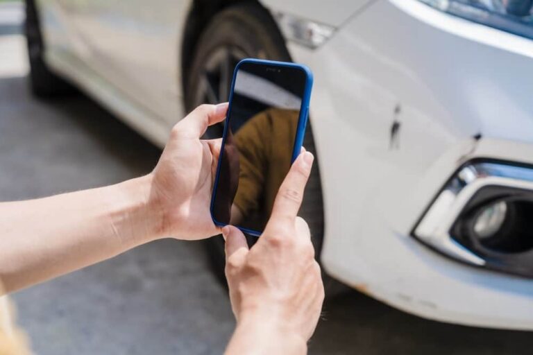 Photo of a woman photographing a scratch on car