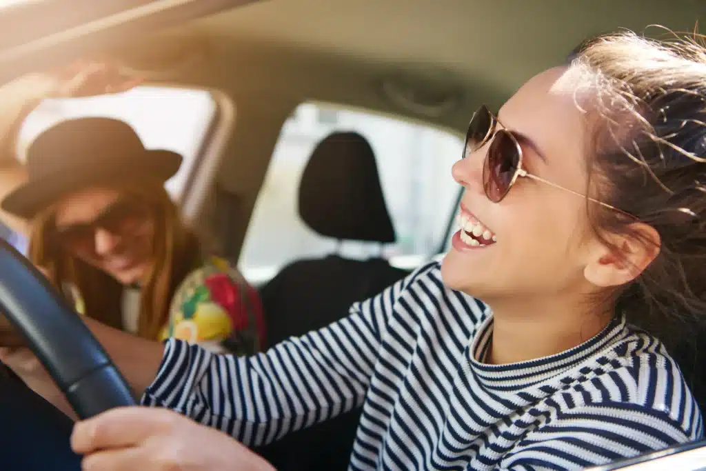 Two young girls laughing while driving