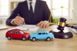 Two toy model cars with car lawyer in the background