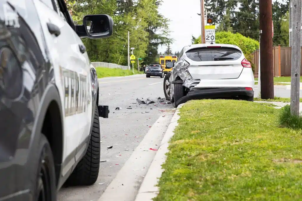 Wrecked car sitting over curb with cop car behind