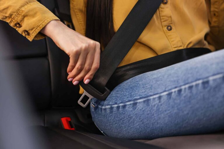 Woman fastening seat belt inside modern car, close-up