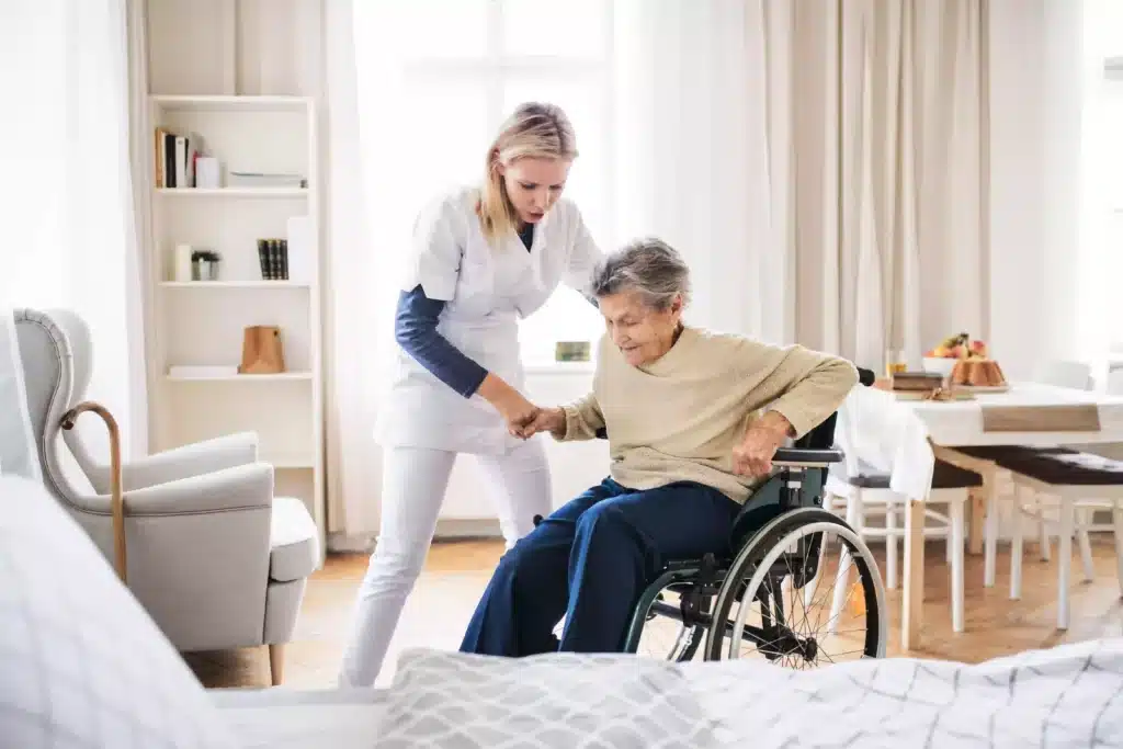 Nurse at nursing home helping elderly lady out of her wheelchair