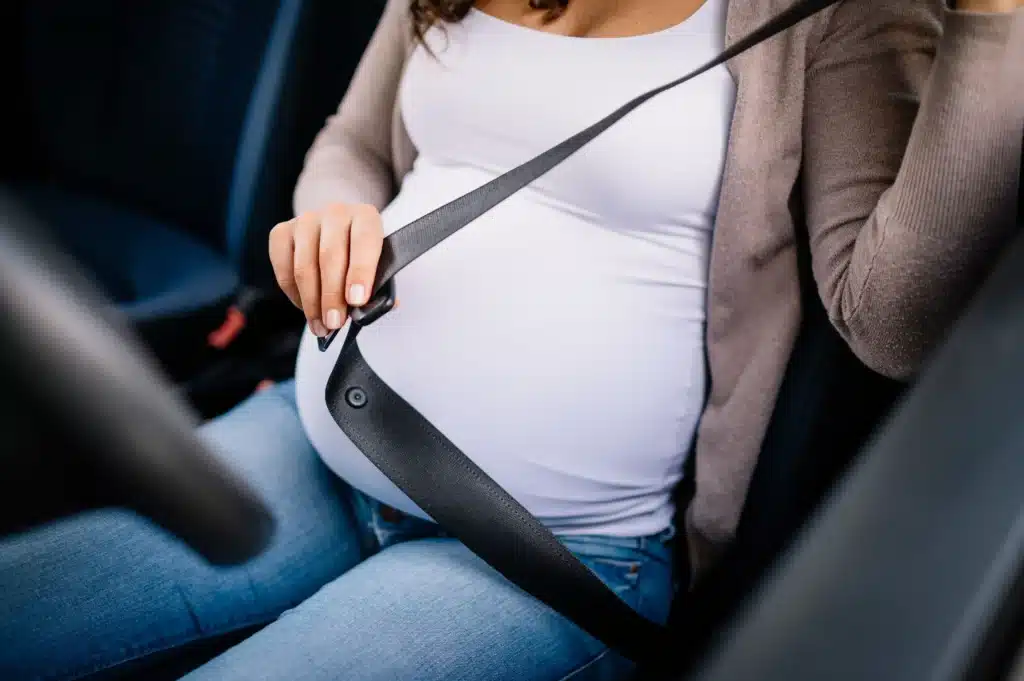 pregnant women securing her seatbelt