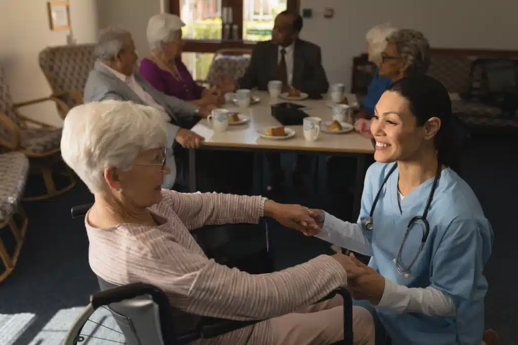 Nursing home nurse bending down and talking with elderly women in wheelchair