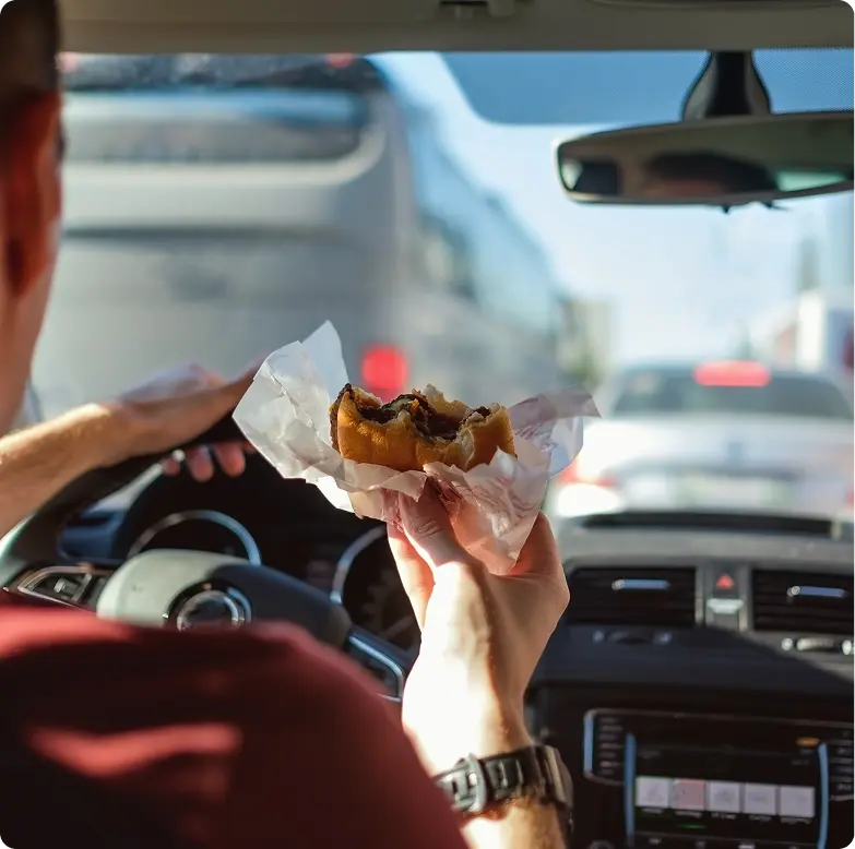 Man driving while eating a burger